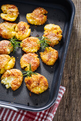 Baked potatoes in metal tray seasoned with rosemary and salt and pepper. Golden and crispy.