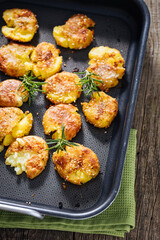 Baked potatoes in metal tray seasoned with rosemary and salt and pepper. Golden and crispy.