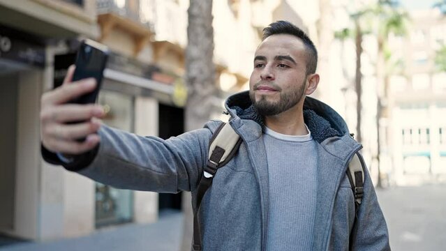 Hispanic man smiling confident taking picture with smartphone at street
