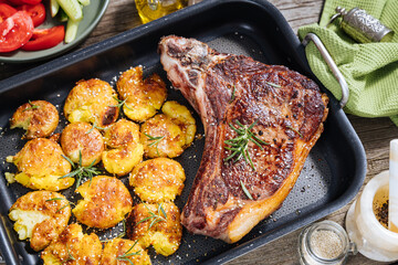 Prime cut of steak with baked potatoes served in metal tray. Seasoned with rosemary, pepper and garlic. Juicy and delicious