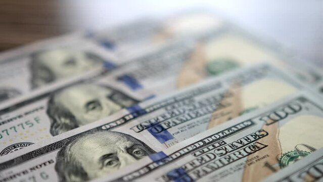 Close-up slow motion shot of 100 dollar bills lying flat on table. Background of money. Neat rows dollars money cash.
