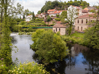 Fototapeta na wymiar Vistas del río con casas reflejadas en la orilla rodeado de naturaleza verde en el pueblo de Allaritz, Orense, verano de 2021 España.