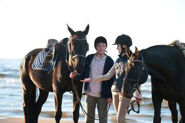 Young couple smiling standing together with horses at wavy sea