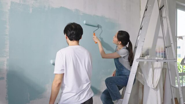 New home,Repair,happy,New life,insurance,carefree relationship,love lifestyle,renovation and decorating concept.Happy Young asian couple choosing blue color and painting walls at new apartment
