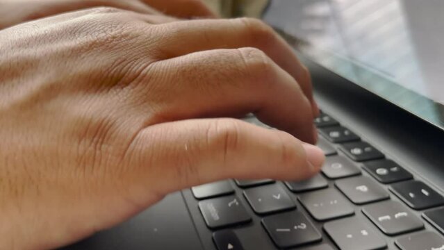 Manos de hombre escribiendo y usando el trackpad en un teclado color negro de iPad Pro. Trabajando en oficina o en casa.