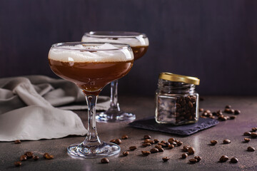 Cold martini espresso cocktail in glasses and coffee beans on the table