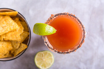 Close up of michelada cocktail with tomato juice, beer and lime in a glass and nachos top view