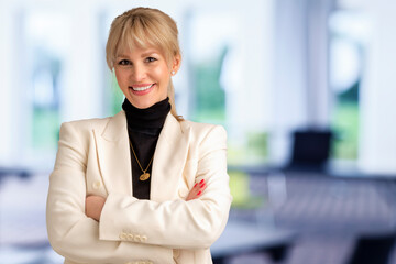Blond haired businesswoman standing with arms crossed at the conference room