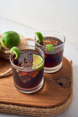 Cuba Libre or long island iced tea cocktail with strong drinks, cola, lime and ice in glass, caribbean drink. Focus Selective.