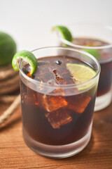 Cuba Libre in a glass with brown rum, cola, mint and lemon, caribbean drink for summer. Focus Selective