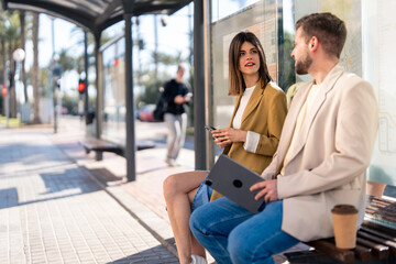 Two people, modern woman and man waiting for bus at bus station.