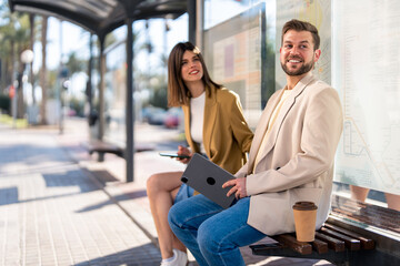 Smiling satisfied business professionals male and female waiting for public transport to go to...