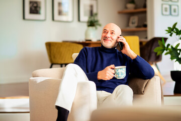 Happy faced man relaxing at home and having a phone call