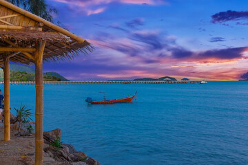 Colourful Skies Sunset over Rawai Beach in Phuket island Thailand. Lovely turquoise blue waters, lush green mountains colourful skies and beautiful views the pier and longtail boats and islands 