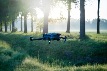 Rehkitzrettung - Drohne mit Wärmekamera fliegt am frühen Morgen die Wiese ab. - obrazy, fototapety, plakaty