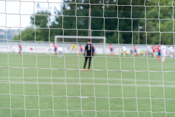 Soccer goal mesh focused on a match with the goalkeeper and players out of focus. . High quality photo