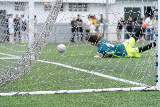View from the back of the net of a soccer goalkeeper clearing the ball. Shot from the back of a focused soccer net. High quality photo