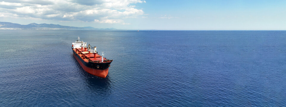 Aerial drone ultra wide panoramic photo with copy space of huge industrial bulk carrier tanker anchored in deep blue Aegean sea