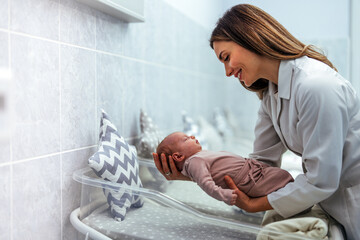 Doctor pediatrician examining new born baby boy in clinic. Nurse dressing infant baby girl. Medical...