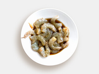 Plate with raw shrimp in teriyaki sauce on a white background, top view. Cooking Asian sea food.