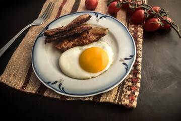 fried egg with bacon on the table