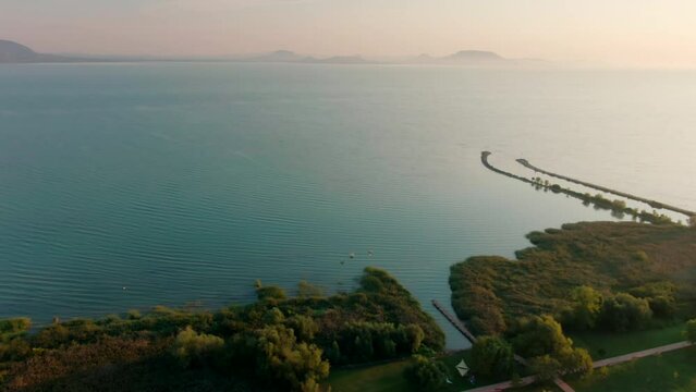 Aerial view of Lake Balaton with longest Pier during Sunset, Hungary, Central Europe. Panoramic perspective of Horizon and Landscape in touristic place for vacation. 4k drone shot