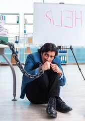 Chained male employee unhappy with excessive work