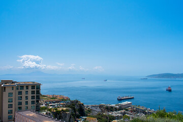 Naklejka premium Gibraltar, Aerial view on buildings, city and coast of sea. Crystal clear blue water against mountains