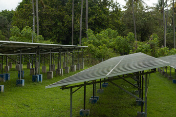 Fototapeta premium Solar power plant energy panels on tropical island Gili Air, Indonesia. Cloudy day, tropical forest