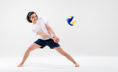 A young volleyball player is training with a ball on a white background. Action, sport, health,...