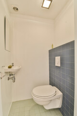 a white toilet in a bathroom with blue tiles on the floor and walls, along with a wall mounted mirror