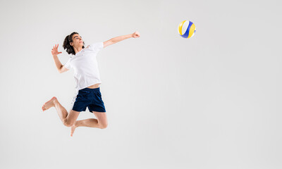 A young volleyball player is training with a ball on a white background. Action, sport, health, team, fitness concept