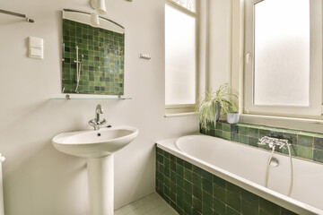 a bathroom with green tiles on the walls and white fixtures in the bathtub is next to the toilet bowl