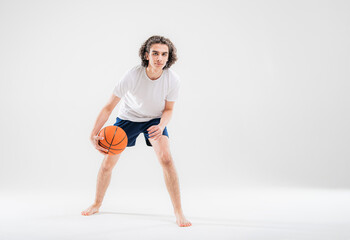 Fototapeta na wymiar Portrait of a boy playing with a basketball on a white background