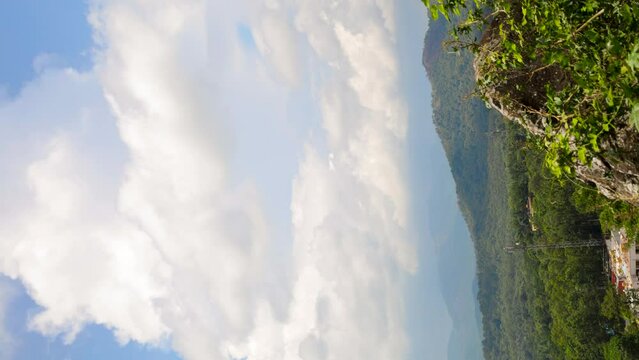 time lapse of a hilly area with trees and other hills in the background - clouds moving in the sky casting shadows