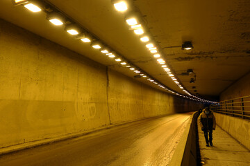Dimly lit urban underpass in Montreal with people walking along the road on a sidewalk