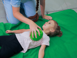 Physical therapist working with little girl in sensory room. Exercising with weighted ball and...