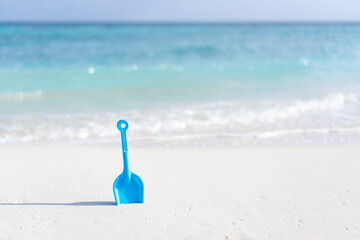 Children's toy shovel on the beach against the background of the ocean in the Maldives.