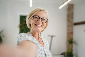 Portrait of one mature blonde caucasian woman with eyeglasses at home