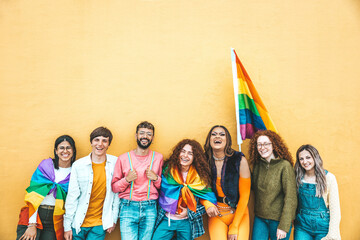 Diverse group of young people celebrating gay pride festival day - Lgbt community concept with guys and girls hugging together outdoors - Multiracial cheerful friends standing on a yellow background - obrazy, fototapety, plakaty