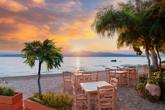 Beautiful sunrise scene on the beach with a terrace and tropical trees illuminated by the sunlight in Nikiana, Lefkada, Greece