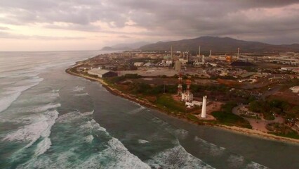Aerial Panning Shot Of Barbers Point Lighthouse Near Splashing Waves, Drone Flying Over Sea Against Sky At Sunset - Oahu, Hawaii