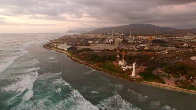 Aerial Panning Shot Of Barbers Point Lighthouse Near Splashing Waves, Drone Flying Over Sea Against Sky At Sunset - Oahu, Hawaii