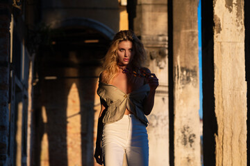 Fototapeta premium Outdoor portrait of a young blonde woman on city street. Sexy woman walking outdoors. Sensual girl posing on street. Fashion model posing on city. Street style summer trend. Fashionable sexy woman.