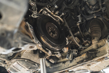 A car on a lift in repair service, the gearbox removed, with visible flywheel. High quality photo