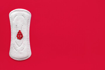 Menstrual pad with red sequins in the form of a drop of blood on a red background. Free space for text. The concept of menstruation in women. Tool to stop bleeding during the menstrual cycle © halcon1