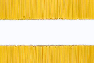 Raw spaghetti on a white isolated background. Background of dry uncooked spaghetti with free space for text in the center. Empty space for design idea. Culinary concept for a restaurant