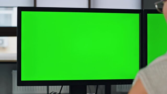 Manager working green pc screen closeup. Two chromakey monitor in home office.