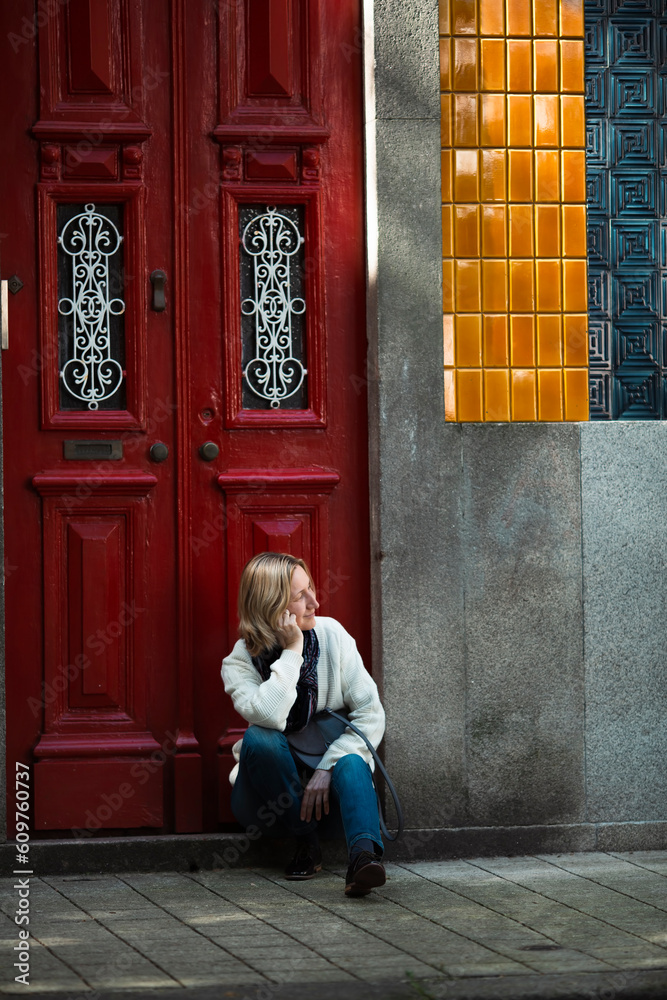 Wall mural A woman sits near the door of a traditional Portuguese town house.