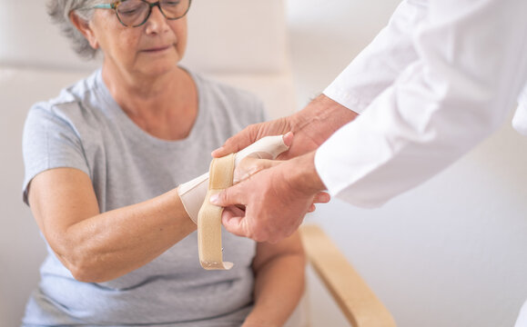 Senior female patient with rhizoarthrosis of the right thumb while wearing a thumb brace with her physical therapist. Elderly woman pain and rehabilitation at the medical center - Powered by Adobe